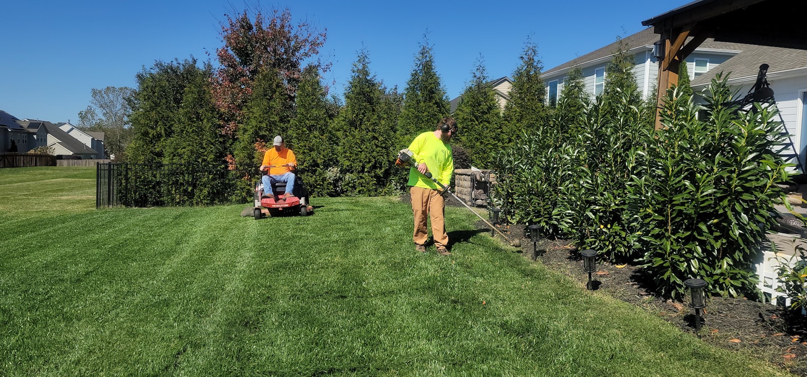 Solo operator pushing a walk-behind mower across a Richardson front yard.